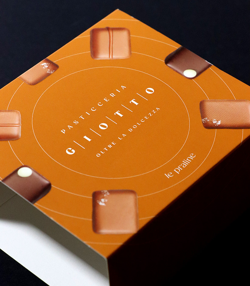 Dettaglio delle guaine in cartoncino GC1 FSC realizzate per i cofanetti di praline Giotto, con verniciatura opaca e rilievo serigrafico.